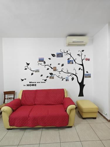 a living room with a red couch and a tree at Casa Vacanza Torino Stadio in Turin