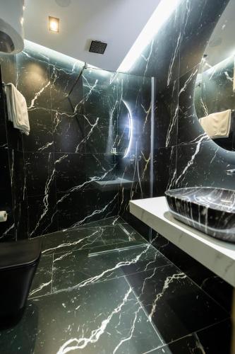 a bathroom with black marble walls and a sink at Hotel Tragjasi in Orikum