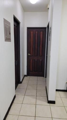 a hallway with two brown doors and a tile floor at Playas del Coco Cocomarindo 23 in Coco