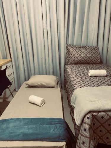 two twin beds in a room with curtains at Apto Suite Aconchegante a 03 minutos do Bairro Horto in Coronel Fabriciano