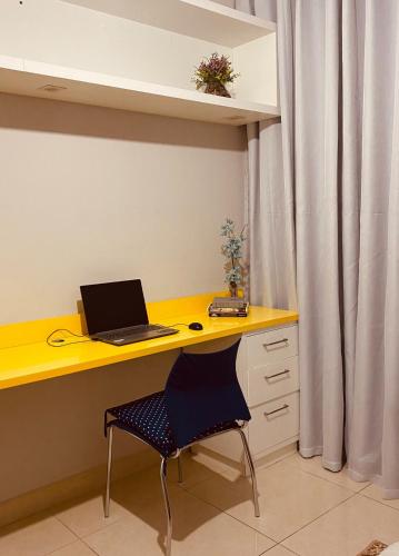 a yellow desk with a laptop computer on it at Apto Suite Aconchegante a 03 minutos do Bairro Horto in Coronel Fabriciano