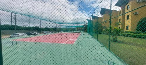 a tennis court is shown through a fence at Winterville Residence Gravatá por Yolo in Gravatá