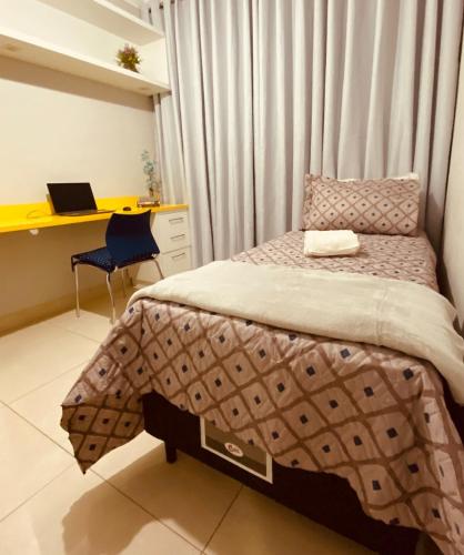 a bedroom with a bed and a desk with a laptop at Apto Suite Aconchegante a 03 minutos do Bairro Horto in Coronel Fabriciano