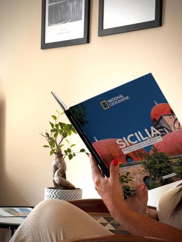 a person is reading a book at Sikelìa Bed & Breakfast in Carini