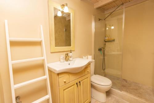 a bathroom with a sink and a toilet and a shower at Cheerful 3 bedroom cottage with indoor fireplace in Avgón