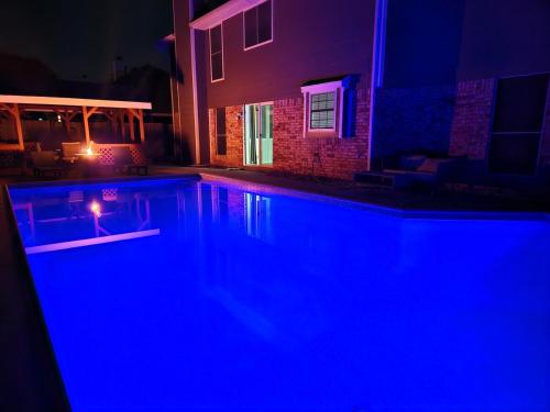 a swimming pool lit up at night with blue lights at 5 BR House with heated pool near DFW and stadium in Grand Prairie