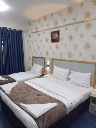two beds in a hotel room with white sheets at Middle East Hotel Dubai in Dubai