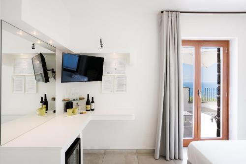 a white living room with a tv and a fireplace at Casa Clementina Marciano in Massa Lubrense