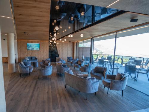 a lobby with couches and chairs and tables and windows at Hotel Purvita by Oberlechner in Maranza