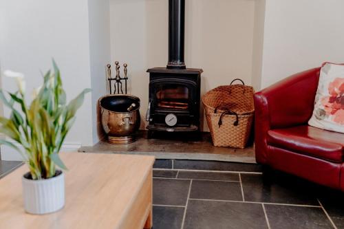 a living room with a stove and a red couch at Spacious Farmhouse Retreat with Hot Tub, sleeps 12 in Llawhaden