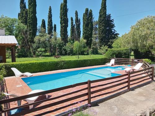 a pool with two chairs and a fence at Cabañas Juaniana in Villa Rumipal