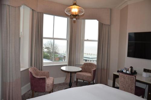 a hotel room with a bed and a table and chairs at voco The Clifton Folkestone by IHG in Folkestone