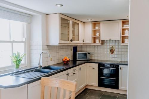a kitchen with white cabinets and a sink at Spacious Farmhouse Retreat with Hot Tub, sleeps 12 in Llawhaden