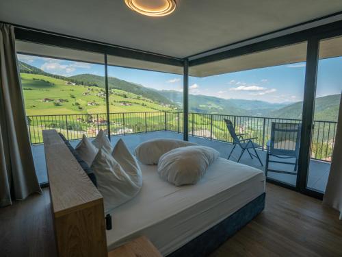 a bedroom with a bed and a balcony with a view at Hotel Purvita by Oberlechner in Maranza
