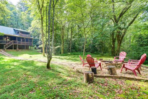 a group of red chairs and a picnic table in a yard at Picturesque Mountain Cabin with Hot Tub and Fire Pit! in Blue Ridge