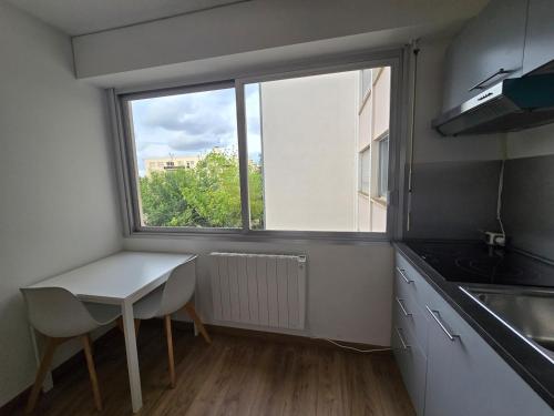 eine kleine Küche mit Tisch und Fenster in der Unterkunft Quiet in Dijon