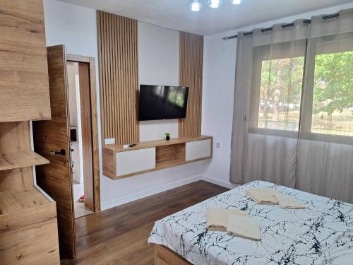 a bedroom with a bed and a television on a wall at Apartmani Park Cuprija in Ćuprija