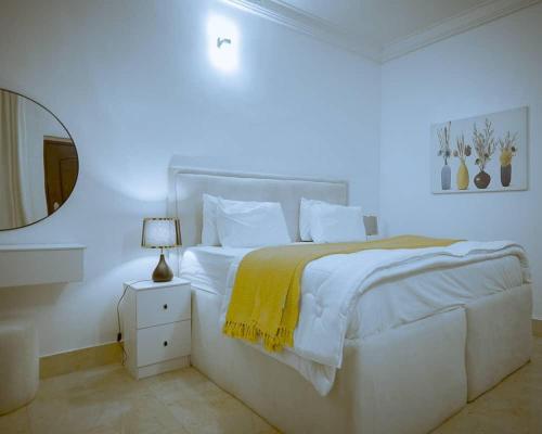 a white bedroom with a white bed and a mirror at Luxury Mini Flat Eleganza Garden Lekki Ajah in Aja