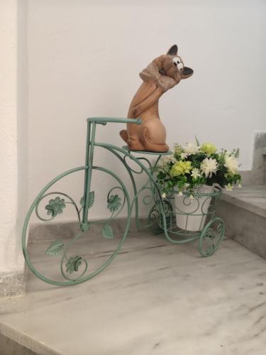 a statue of a dog riding a bike with flowers at Boulitos 1 in Kavos