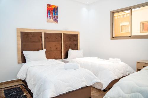 three beds in a room with white sheets at Tifawine Stay Guest House Social Stay and Oceanview Rooms in Imsouane