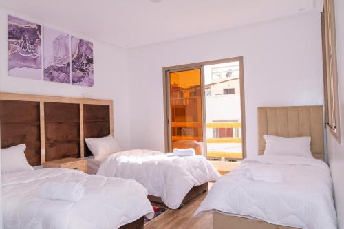 a bedroom with two beds and a window at Tifawine Stay Guest House Social Stay and Oceanview Rooms in Imsouane