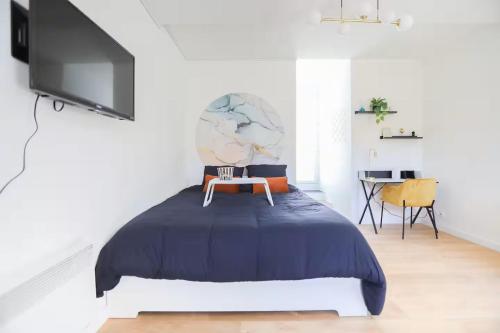 a bedroom with a bed with a tv on the wall at Studio calme avec extérieur et entrée autonome in Saint-Sébastien-sur-Loire