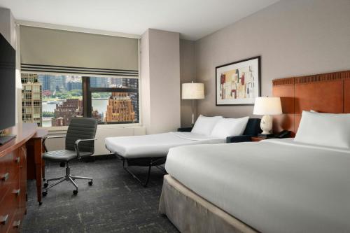 a hotel room with two beds and a desk and a window at Courtyard New York Manhattan/Midtown East in New York