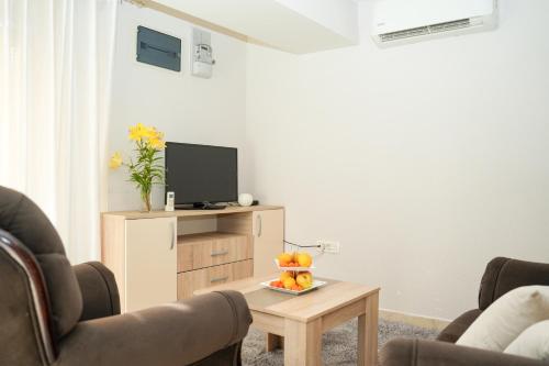 a living room with a tv and a table with fruit on it at Apartments Bućin in Kotor
