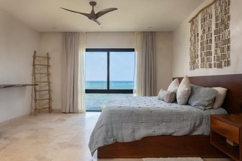 a bedroom with a bed and a large window at 3BR Beachfront with Private Rooftop at Tankah Bay in Tulum