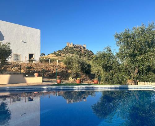 a swimming pool in front of a house with a hill at Casa Caraza. Un olivar con vistas al castillo de Juego de Tronos in Almodóvar del Río