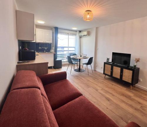 サン・シプリアン・プラージュにあるLe perroquetの赤いソファとキッチンのあるリビングルーム