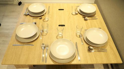 a wooden table with white plates and silverware on it at Résidence Coeur de Lourdes in Lourdes