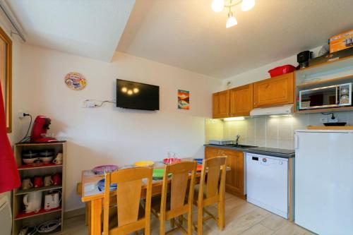une cuisine avec une table, des chaises et un réfrigérateur dans l'établissement Au bon endroit N3 - Appartement 2 pièces 5/7 personnes - proche pistes - Belle vue montagne, à Orcières