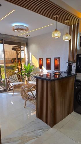 a living room with a bar with chairs and tables at Blue Bay Village Appartement Cocooning en Rez-de-Jardin avec Vue Mer dans une Résidence Sécurisée à Moulay Abdallah près El Jadida in Moulay Abdallah