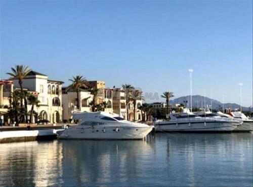 three boats are docked in a harbor with buildings at Marina Smir Compounds Pool & Beach in Marina Smir