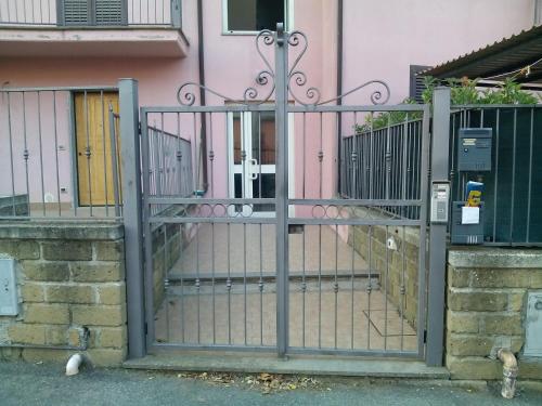 ein Metalltor vor einem rosa Haus in der Unterkunft Appartamento 2 a Marta nel Lago di Bolsena in Marta