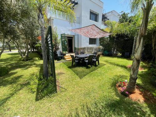 a house with a table and chairs in the yard at BEAU TRIPLEX EN RESIDENCE in Skhirat