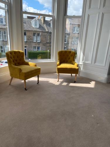 two yellow chairs sitting in a room with windows at Kingston Guesthouse in Edinburgh