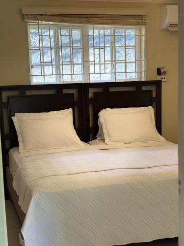 a bedroom with a large bed with white sheets and pillows at Patch&Porch Cottage in Port Antonio