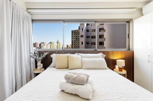a bedroom with a white bed with a large window at BSR Luxe Studio next to Allianz Park w Rooftop Pool and Pet Friendly in São Paulo