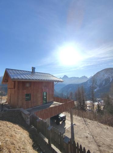 a house on a hill with the mountains in the background at BATAJA - Dolomites Lodge in Valle di Cadore