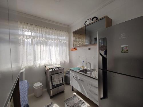 Una pequeña cocina con nevera y fregadero. en Apê da Pê, en Praia Grande