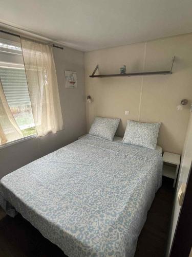 a bedroom with a bed with a blue comforter and a window at Casa Cany in Barreiros
