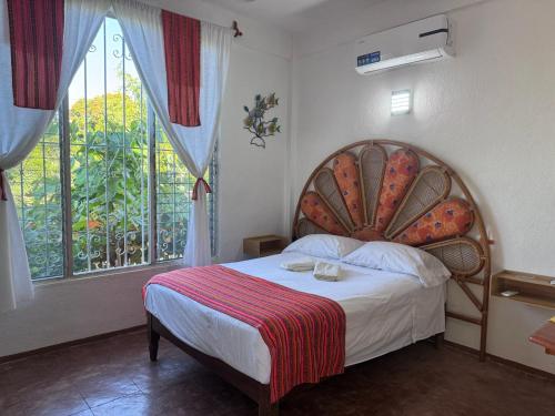 una camera da letto con un letto con una grande finestra di Casa Icaco a Puerto Escondido