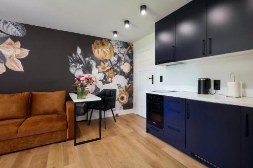 a kitchen with blue cabinets and a table with flowers at Leśny Dworek - Pokoje & Apartamenty in Białka Tatrzanska