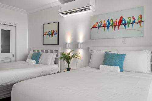 two beds in a white room with paintings on the wall at Condado Lagoon by Otium in San Juan