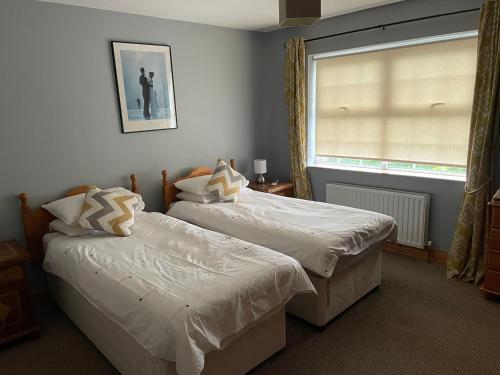 two beds in a room with a window at Fermanagh lakeside Self Catering in Corranny