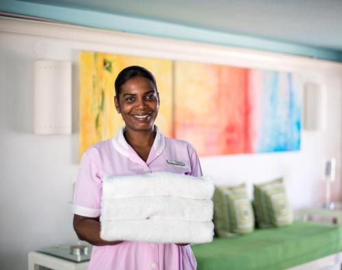a woman in a hospital holding a stack of towels at Deja Resort All Inclusive in Montego Bay