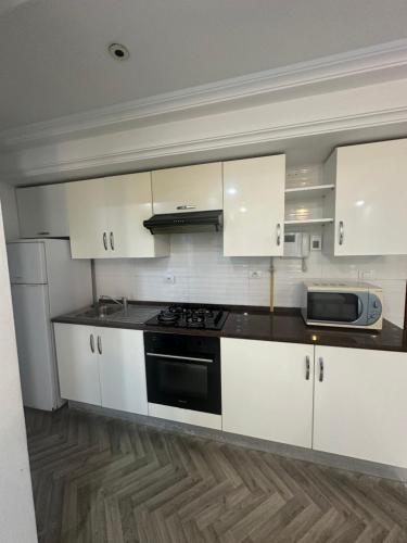 a kitchen with white cabinets and a black stove at Coquette appart de plage in Hammam Sousse