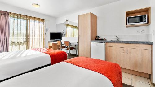 a hotel room with two beds and a kitchen at Bella Vista Motel Rotorua in Rotorua